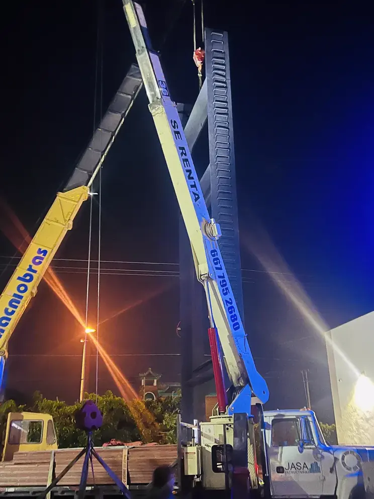 Maniobra nocturna de montaje de anuncio con dos grúas