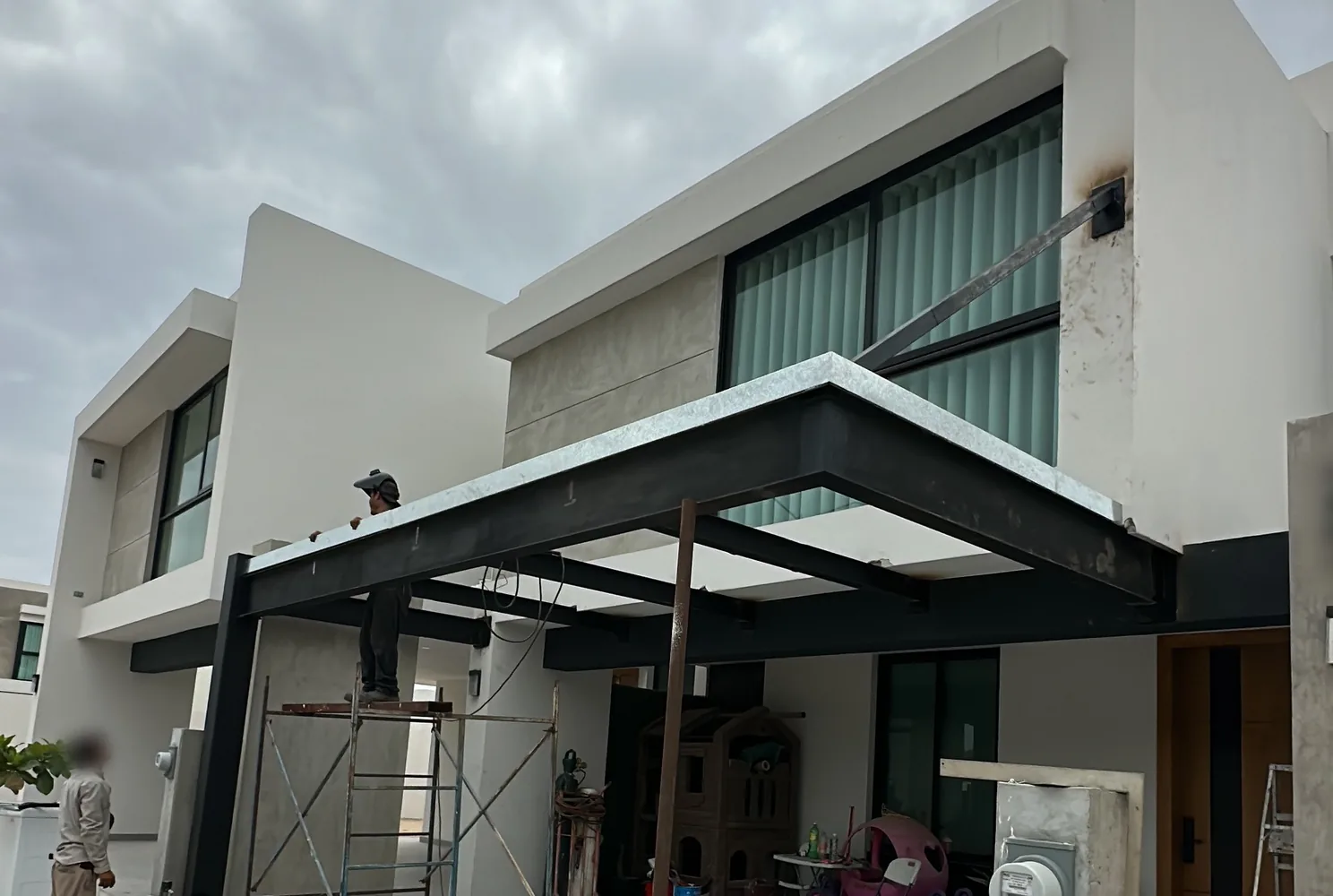 Marquesina volada de acero negro con tensor frente a una residencia