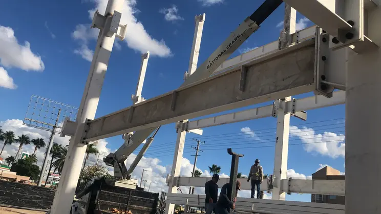 Izaje de viga con grúa y cuadrilla señalando